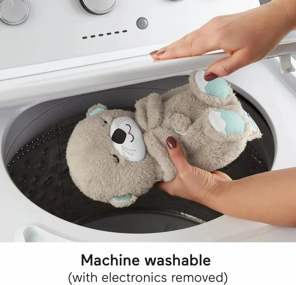 Person holding a machine-washable plush toy with electronic components above a washing machine.