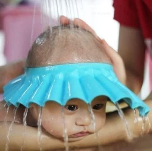 Child with a blue shower cap being washed by water