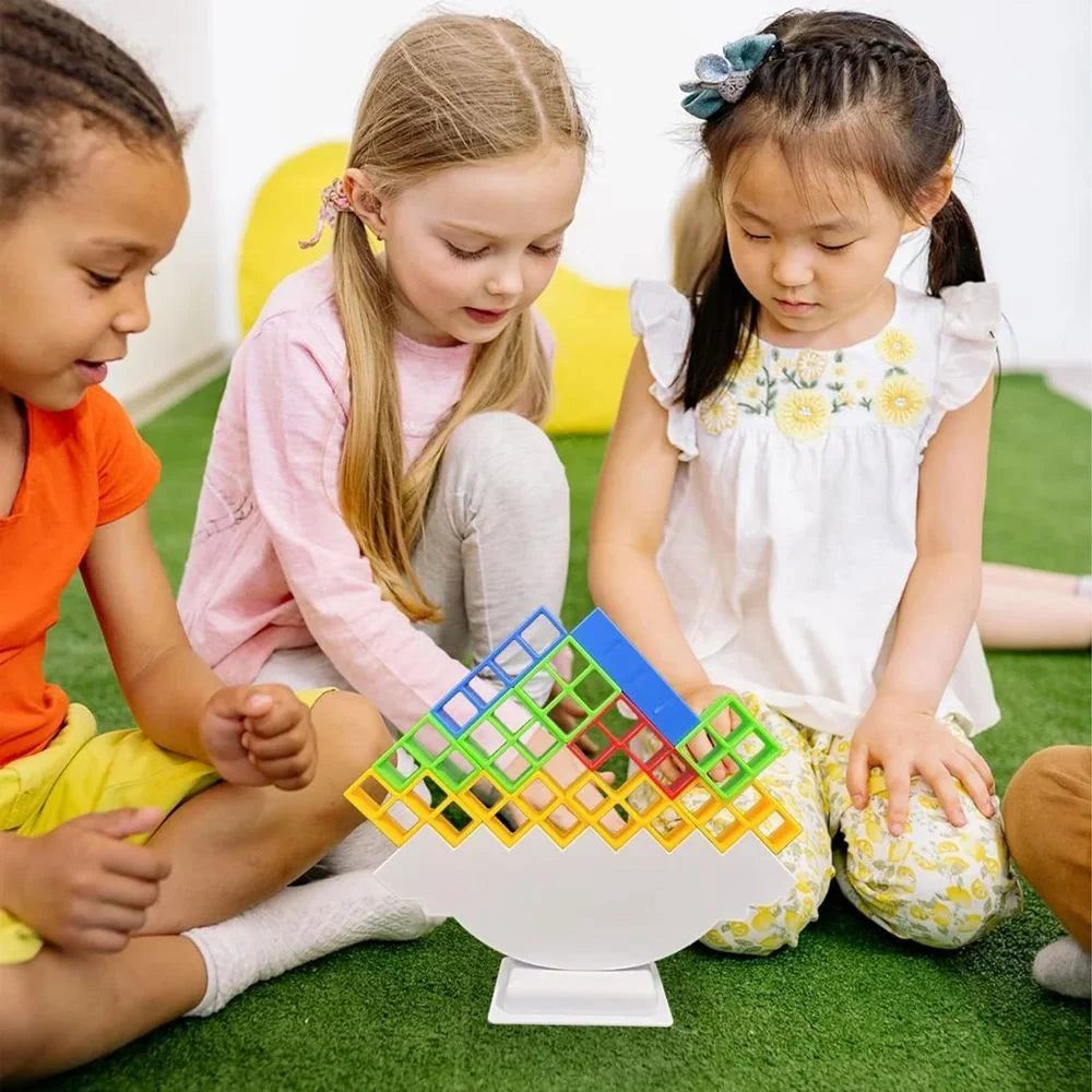 Three children playing with a colorful geometric toy on a green surface.